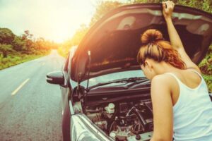 A woman looks in her vehicle's engine